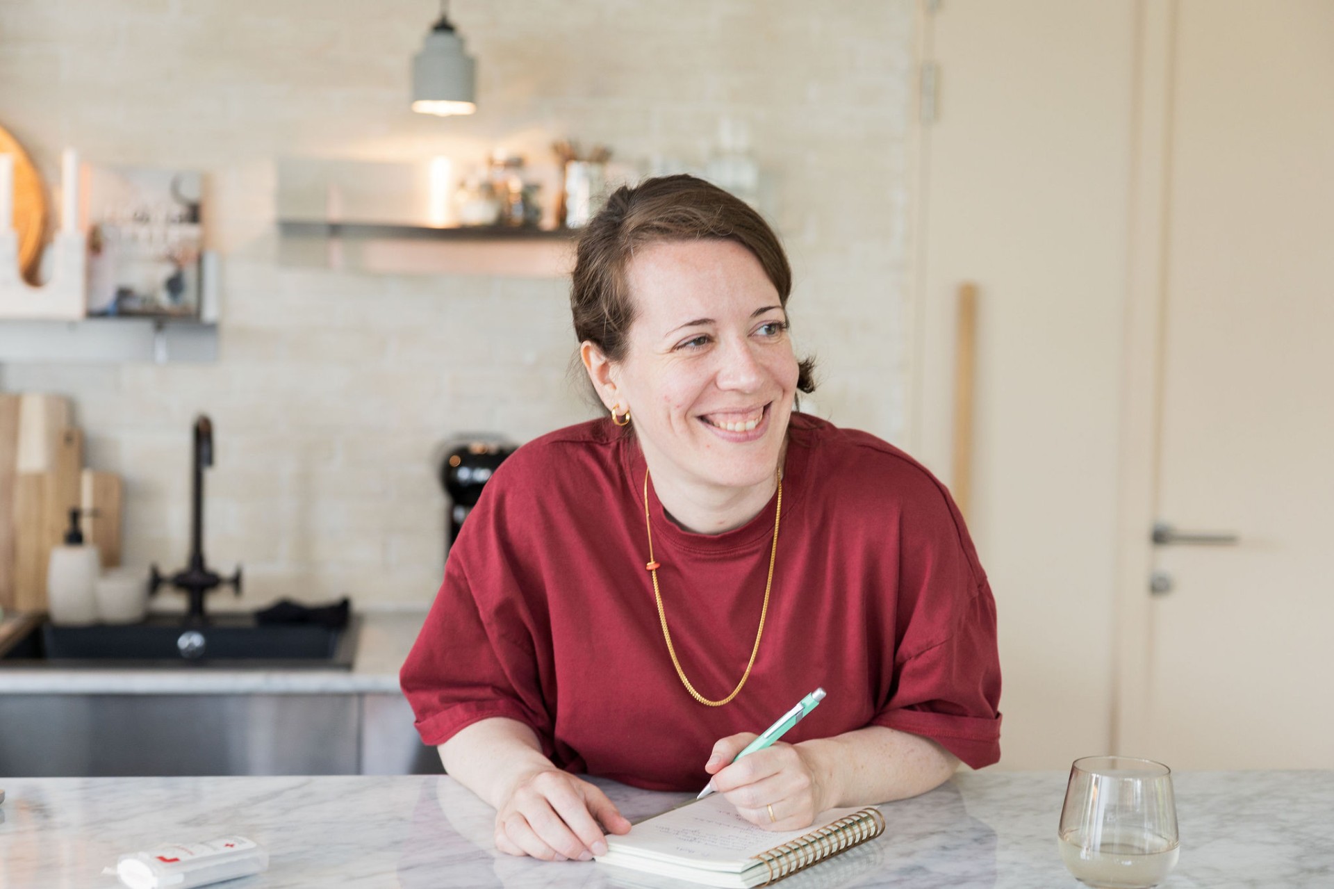 Ann schrijvend in een notitieboekje aan de keukentafel