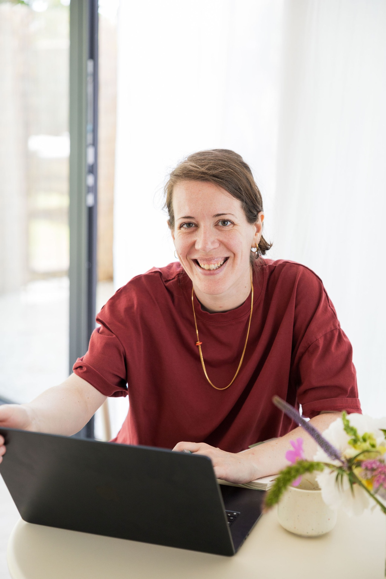 Ann aan het werk achter haar laptop, glimlachend
